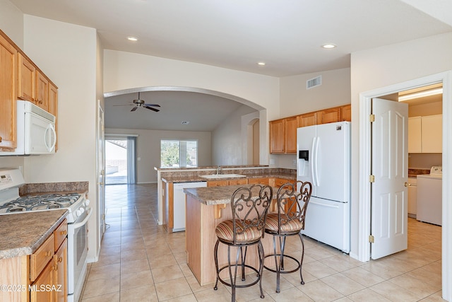 kitchen featuring washer / dryer, kitchen peninsula, sink, white appliances, and light tile patterned floors