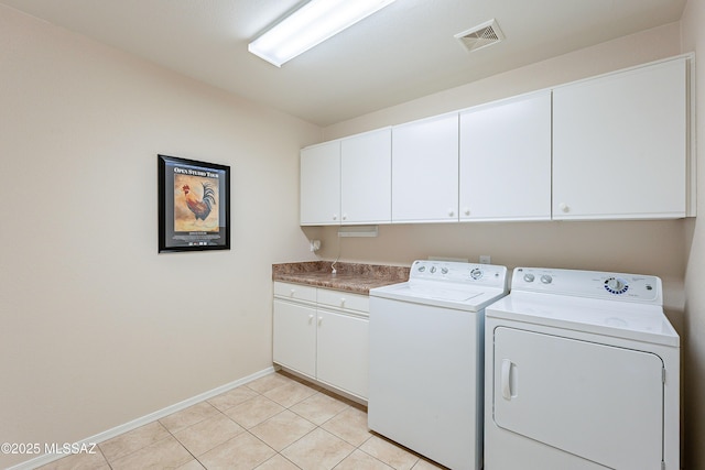 laundry area featuring light tile patterned floors, washer and dryer, and cabinets