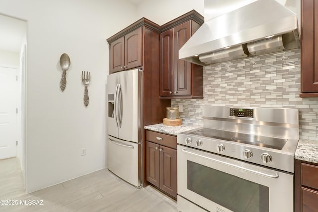 kitchen with exhaust hood, stainless steel appliances, decorative backsplash, light stone countertops, and dark brown cabinetry