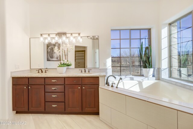 bathroom with tiled tub and vanity