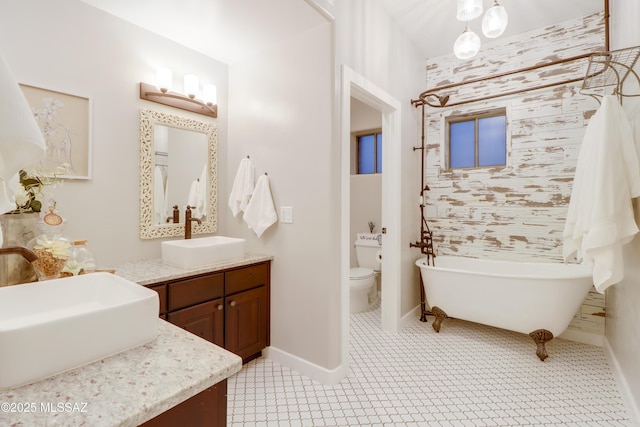 bathroom featuring toilet, vanity, a tub, and tile patterned flooring