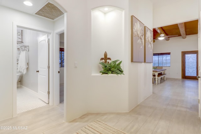 hallway featuring light hardwood / wood-style flooring, beam ceiling, and wood ceiling