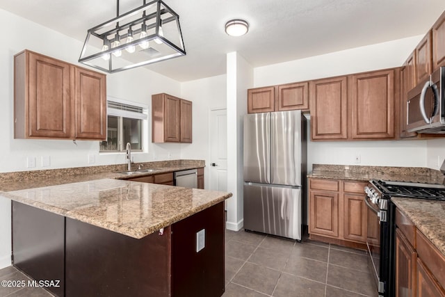 kitchen with pendant lighting, sink, dark tile patterned floors, appliances with stainless steel finishes, and light stone counters