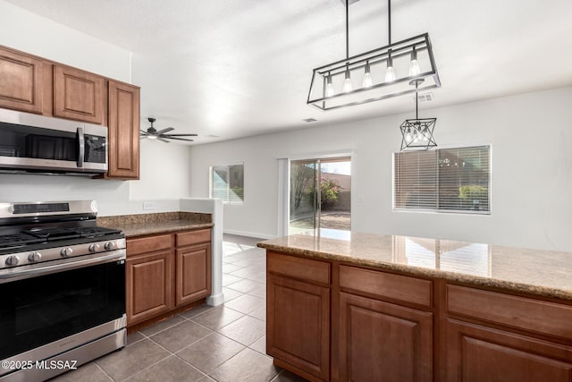 kitchen featuring ceiling fan, appliances with stainless steel finishes, pendant lighting, and dark tile patterned floors