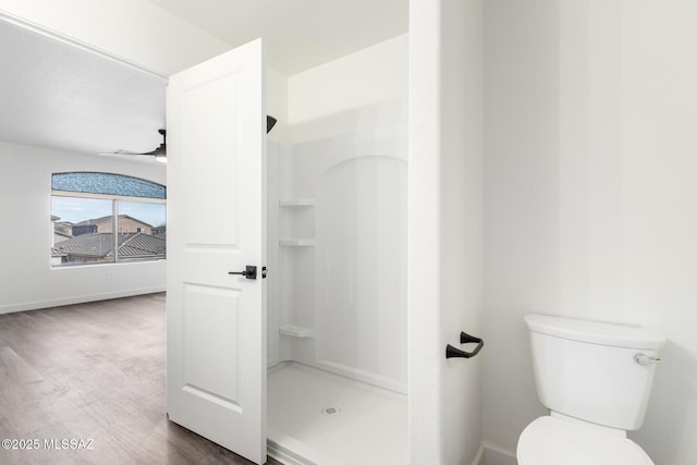 bathroom with toilet, ceiling fan, a shower, and hardwood / wood-style floors