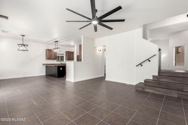 unfurnished living room featuring ceiling fan, sink, and dark tile patterned floors