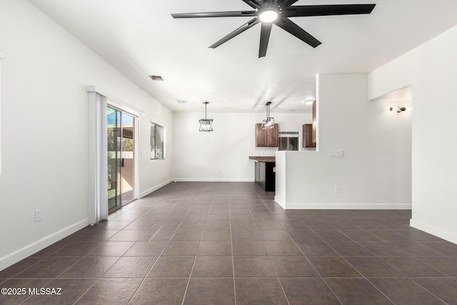 unfurnished living room featuring ceiling fan with notable chandelier