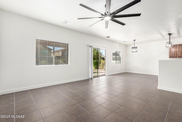 unfurnished room with ceiling fan and dark tile patterned floors