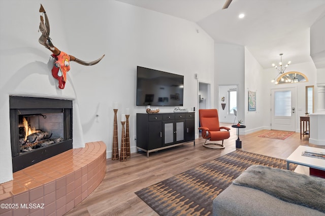 living room with a notable chandelier, hardwood / wood-style flooring, a fireplace, and high vaulted ceiling