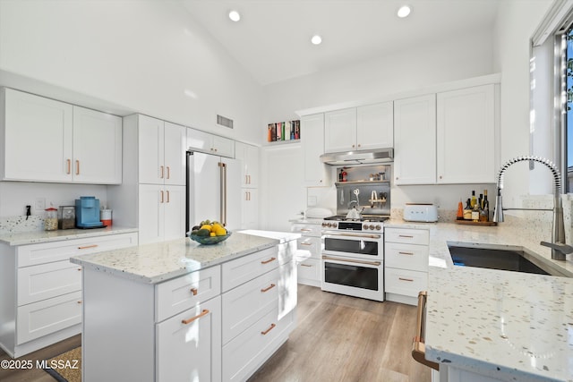 kitchen featuring white cabinetry, high quality appliances, sink, and light stone counters