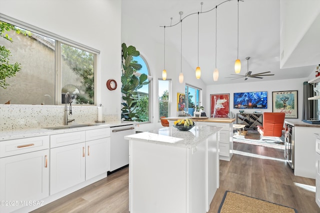 kitchen with light stone counters, sink, white cabinets, and dishwasher