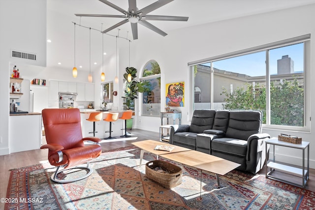 living room with dark wood-type flooring, a towering ceiling, ceiling fan, and sink