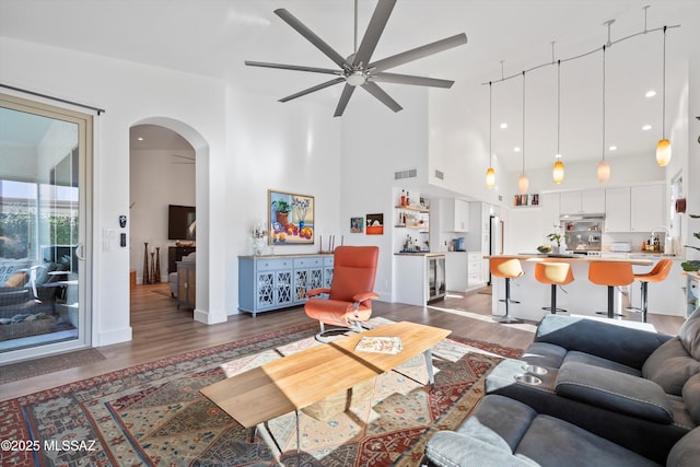 living room featuring wine cooler, a towering ceiling, dark hardwood / wood-style floors, and ceiling fan