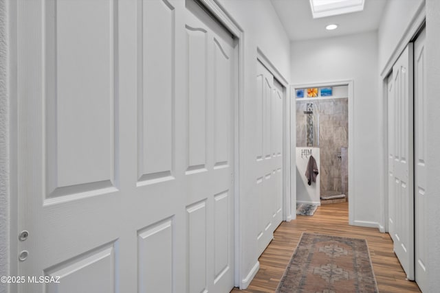 corridor featuring hardwood / wood-style floors and a skylight