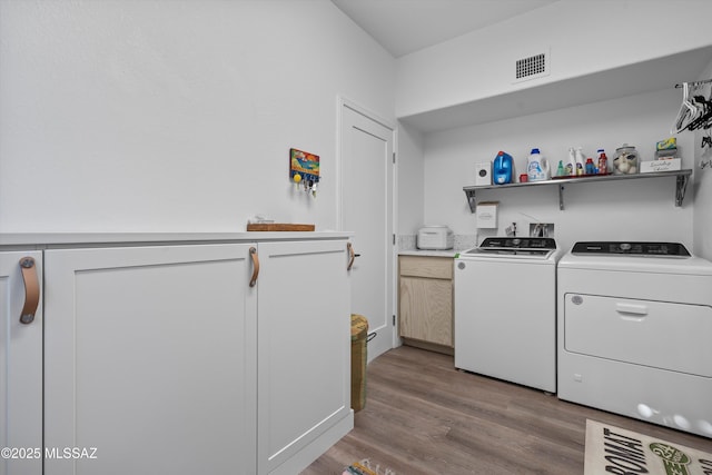 laundry area featuring cabinets, separate washer and dryer, and light hardwood / wood-style flooring