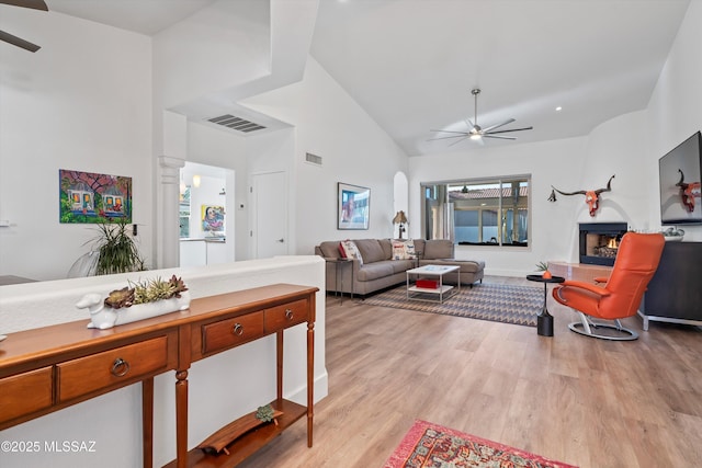 living room with high vaulted ceiling, light hardwood / wood-style floors, decorative columns, and ceiling fan