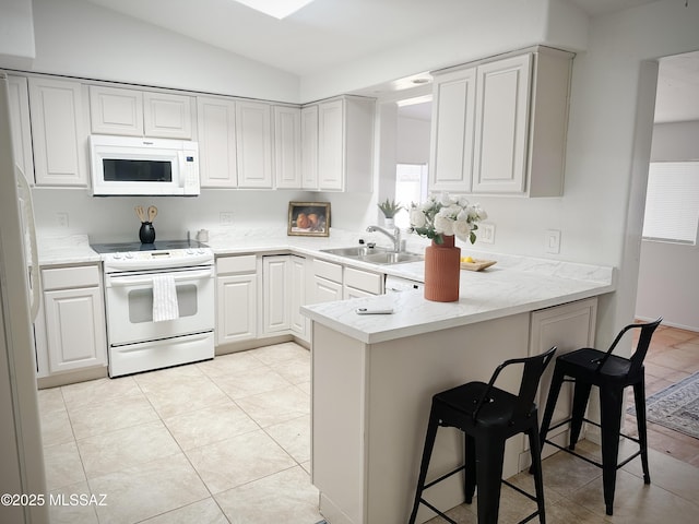 kitchen featuring a breakfast bar, kitchen peninsula, sink, white appliances, and light tile patterned floors