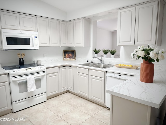 kitchen with white appliances, light tile patterned flooring, vaulted ceiling, white cabinets, and sink