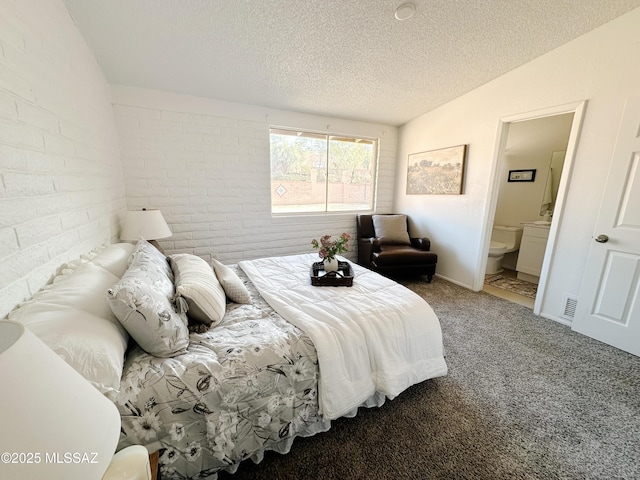 carpeted bedroom featuring ensuite bath, vaulted ceiling, brick wall, and a textured ceiling