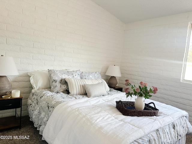 bedroom featuring lofted ceiling and brick wall