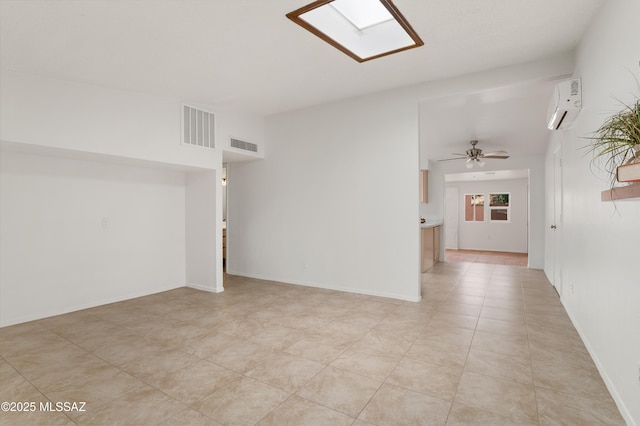 tiled spare room featuring an AC wall unit, a skylight, and ceiling fan