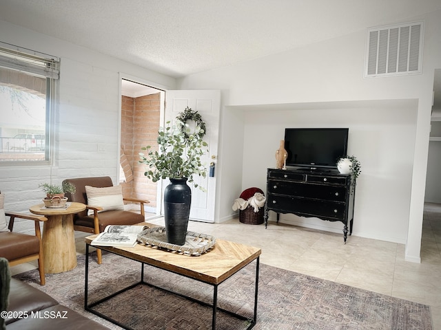 living room with a textured ceiling, light tile patterned floors, and lofted ceiling