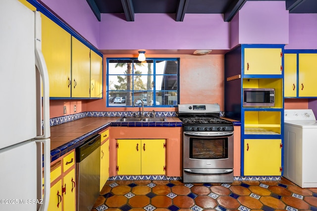 kitchen featuring sink, appliances with stainless steel finishes, tile counters, washer / clothes dryer, and beamed ceiling