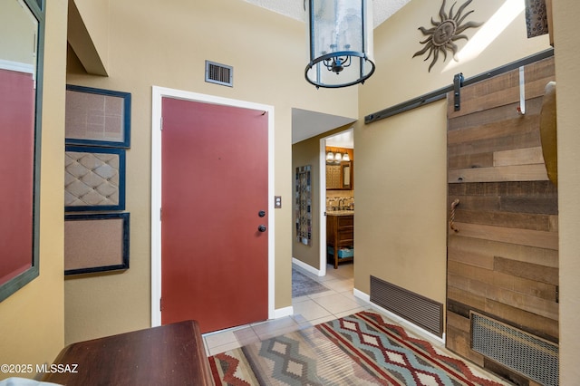 entryway featuring a high ceiling, light tile patterned floors, and a barn door