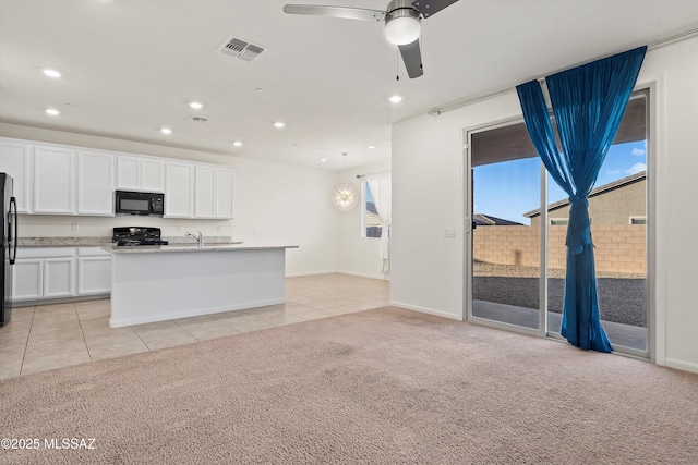 kitchen with white cabinetry, range, light carpet, an island with sink, and ceiling fan