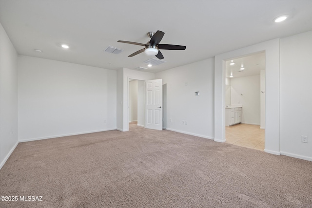 unfurnished bedroom featuring light colored carpet, ceiling fan, and ensuite bathroom