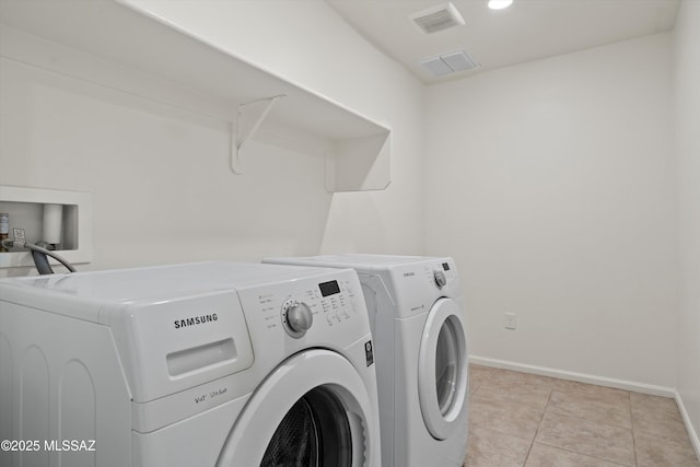 clothes washing area featuring light tile patterned floors and washer and clothes dryer