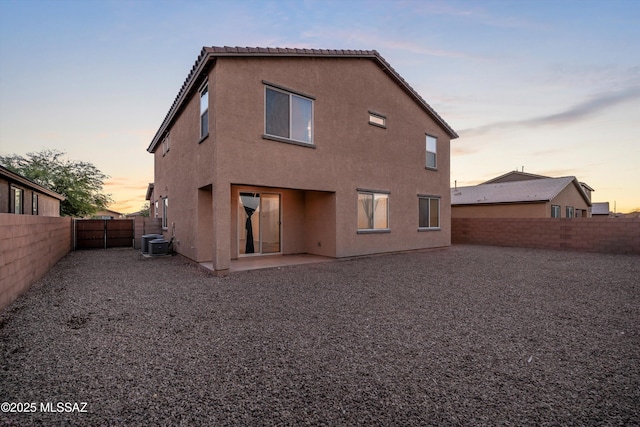 back house at dusk featuring central AC unit and a patio area