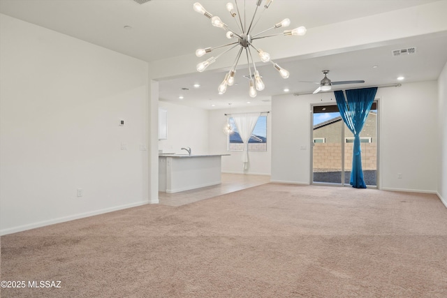 unfurnished living room featuring light carpet, sink, and ceiling fan with notable chandelier