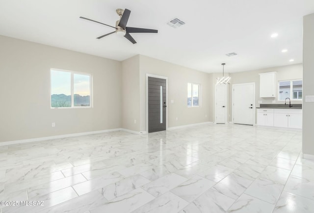 unfurnished living room with marble finish floor, visible vents, a sink, plenty of natural light, and baseboards