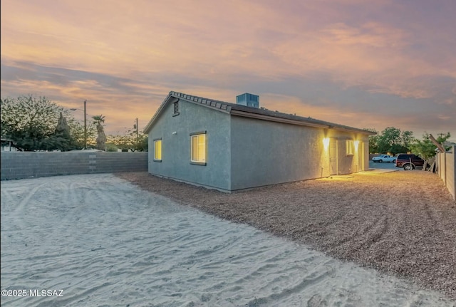 view of side of home with central AC unit and stucco siding