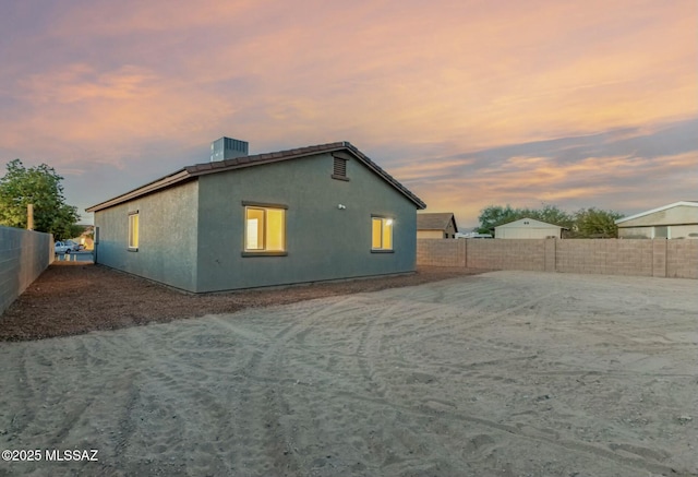 view of side of home with central AC unit, a fenced backyard, and stucco siding