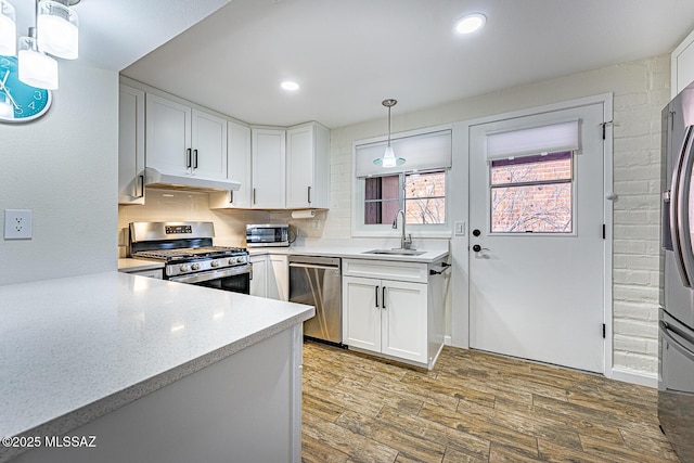 kitchen with decorative light fixtures, decorative backsplash, sink, white cabinetry, and stainless steel appliances