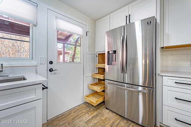 kitchen featuring sink, wood-type flooring, stainless steel fridge with ice dispenser, and white cabinetry