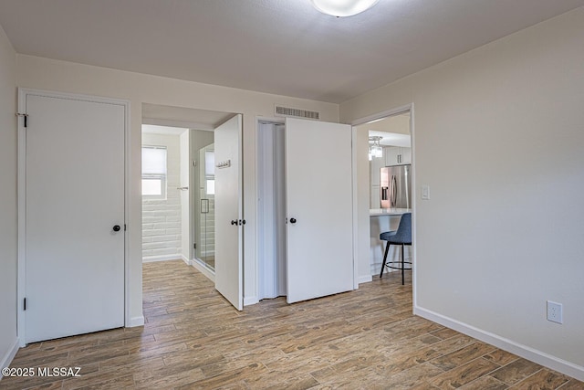 unfurnished bedroom featuring wood-type flooring and stainless steel fridge