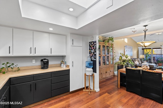 kitchen with decorative light fixtures, white cabinetry, hardwood / wood-style flooring, and a skylight