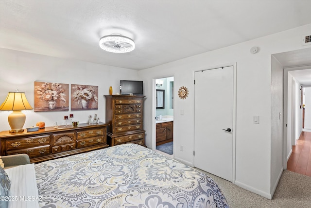 bedroom featuring light carpet and ensuite bath