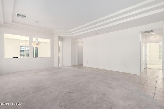 spare room with a chandelier, a raised ceiling, and light tile patterned flooring