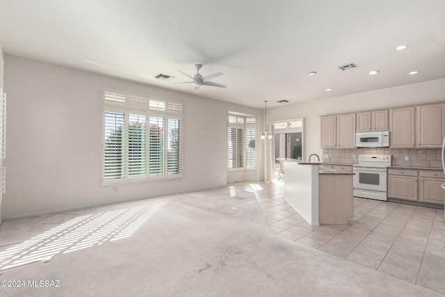 kitchen with hanging light fixtures, backsplash, light colored carpet, white appliances, and ceiling fan with notable chandelier