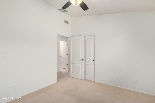 unfurnished bedroom featuring ceiling fan, a closet, and light carpet