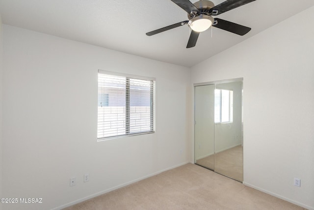 unfurnished bedroom with ceiling fan, a closet, light colored carpet, and multiple windows