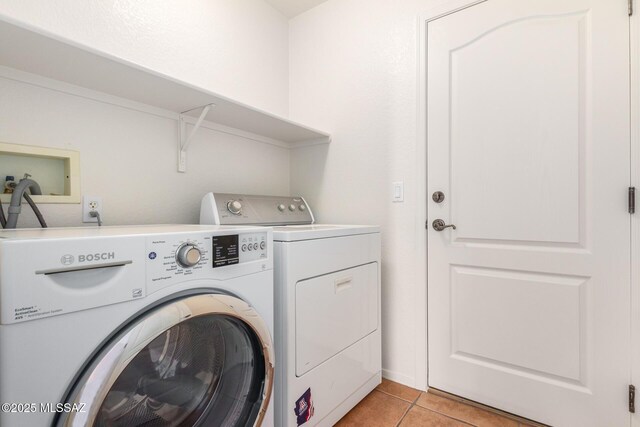 washroom with light tile patterned floors and washing machine and dryer