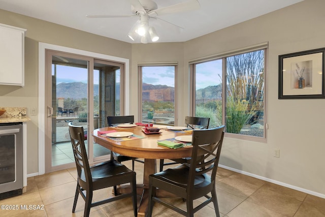 dining space featuring wine cooler, light tile patterned floors, ceiling fan, and a mountain view