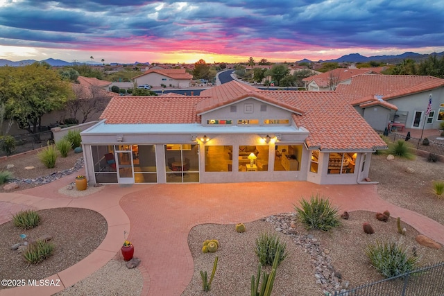 back house at dusk featuring a patio and a sunroom