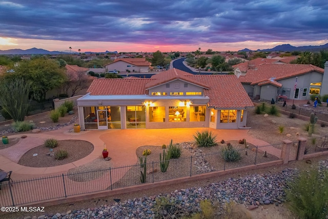 back house at dusk with a sunroom, a mountain view, and a patio