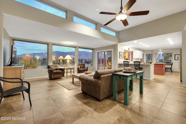 living room with ceiling fan, light tile patterned floors, and a high ceiling